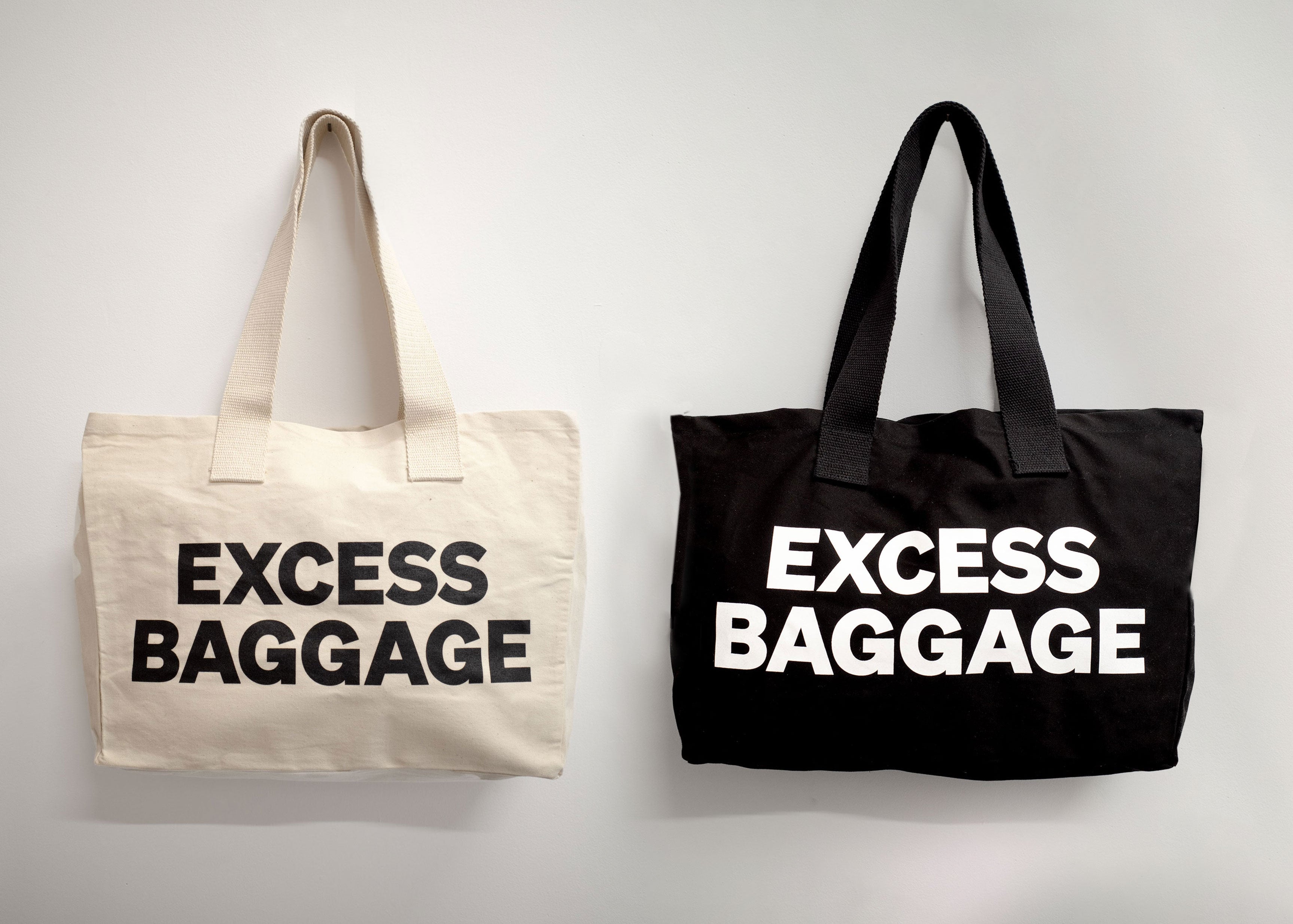 Two tote bags with 'EXCESS BAGGAGE' text on a light gray background